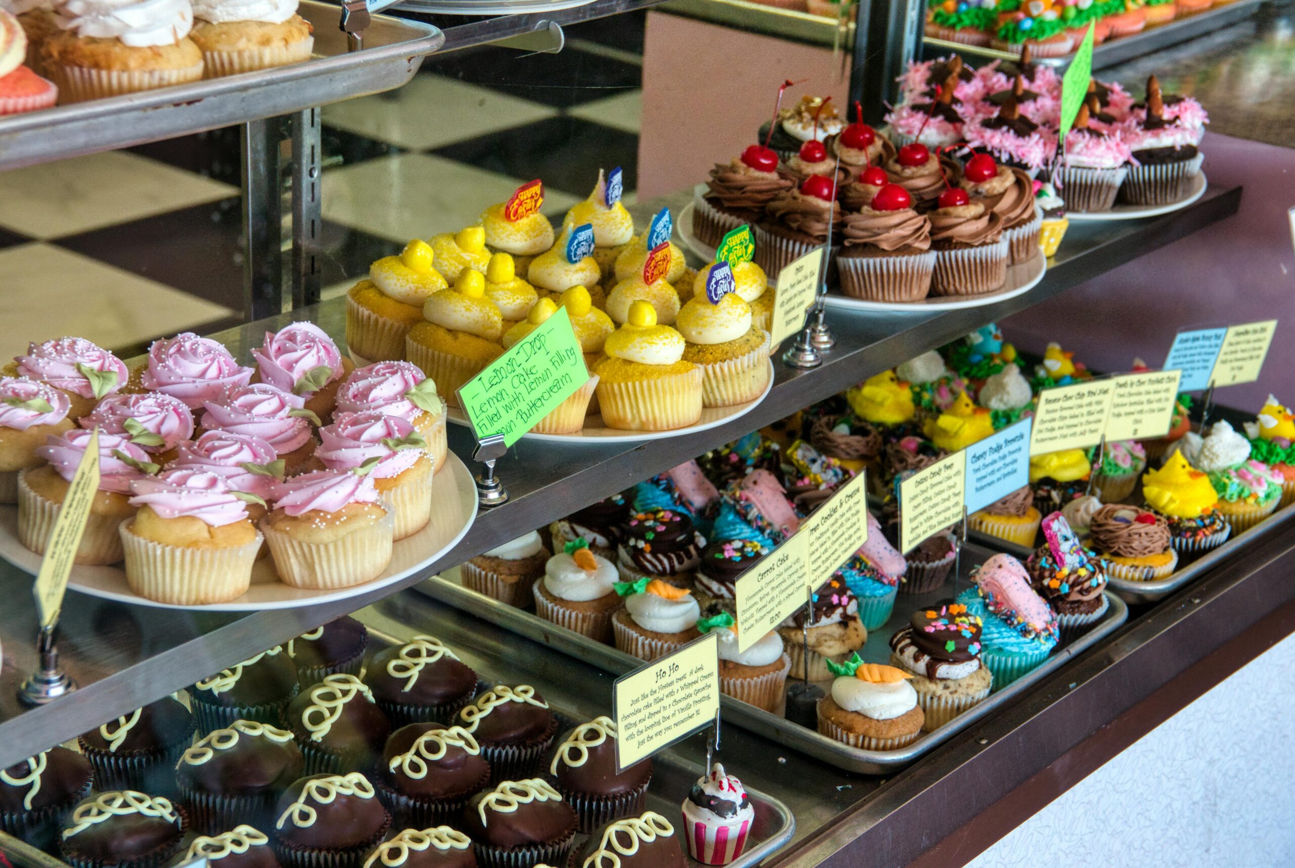 Showcase of colorful and decorative cupcakes in a bakery display.